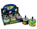 A retail display box and three individual printed spinning ashtrays shown on a stylized teal and gray background. The ashtrays feature colorful graphics including a cannabis leaf and tropical illustrations, with metallic silver bases and black tops.