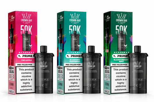 Three Crown Bar PRIME 50K Hypermax pre-filled pods with their colorful retail boxes displayed side by side on a white background. The pods are black with silver accents, and the boxes feature vibrant pink, teal, and dark green designs with flavor labels including Two Apple, Blueberry Lemonade, and Blackcurrant Mint.